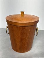 Front view of teak ice bucket with lid and brass accents.