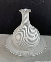 White and black spiral patterned Murano glass vase on top of matching saucer, showing overall design and condition.