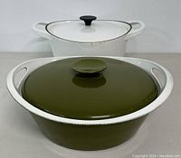 Two cast iron Dutch ovens, one white enamel and one olive green enamel, showing general shape and lids