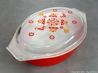 Large red Pyrex bowl with clear glass lid with floral and bird decal