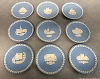 Grid layout photo of all 9 Wedgwood blue jasperware collector plates showing various white relief architectural designs and laurel wreath borders.