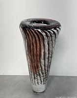 Front view of tall art glass vase showing ribbed texture and coloration in brown, white, and clear glass with bubble texture at base.