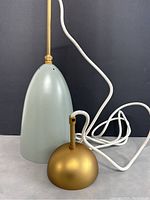 Lamp assembly showing conical shade, brass-tone canopy and white fabric cord