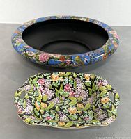 Square ashtray with intricate floral and bird motifs on black, showing design and shape with handles.