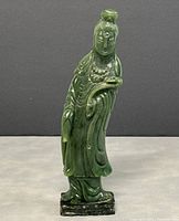 Front view of the carved jade Guan Yin statue standing on a rectangular base, showing detailed robe and facial features.