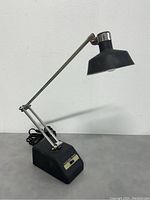 Side view of the desk lamp showing its adjustable arm, black shade, base with control switch and power cord.
