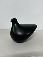 Side view of black modernist ceramic bird sculpture showing smooth curves and minimalist form.