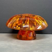 Front angle view of the vintage amber acrylic mushroom paperweight showing internal amber and yellow swirls and glossy finish.