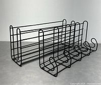 Side view of the black metal wire coat rack showing four hooks and top rack surface.