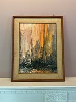 Frontal view of framed oil painting showing boats with tall masts and colorful background.