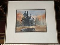 Full view of the framed watercolor painting showing the forest scene with trees and water.