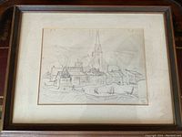 Photo of framed pencil sketch artwork showing village buildings and church steeple, frame and matting visible