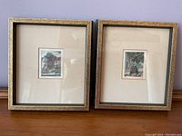 Front view of two framed artworks side by side on a wooden surface, showing the overall appearance and frame style.