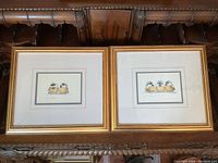 Two framed artworks of bird illustrations labeled "Duo" and "Trio" on a wooden surface