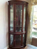 Full front view of wood and glass curio cabinet with curved glass panels and doors, showing size and style.