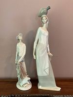 Front view of both porcelain figurines: man and woman with bird.