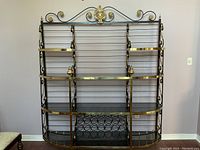 Full front view of the large metal shelving unit with glass shelves and decorative gold-tone metal accents.