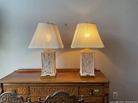 Pair of ceramic table lamps on wooden dresser, showing overall design and size.