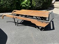 Side view of vintage wooden platform trolley with metal frame and integrated weigh scale at front, showing wood grain and wear from age.