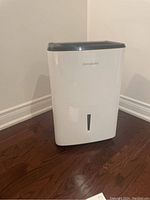 Full front view of the white Frigidaire standup dehumidifier, showing its compact size and water level indicator.