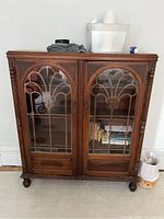 Front view of antique bookcase with glass doors showing carved muntins and feet.