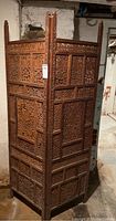 View of the carved wood screen from a corner angle showing both hinged panels and intricate carving.