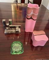 Overview of all four items: metal abstract art piece, pink ceramic vase, matching trinket box, and green glass ashtray with bird motif.
