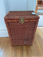 Front view of the wicker hamper showing rectangular shape, woven wicker material, and metal latch.