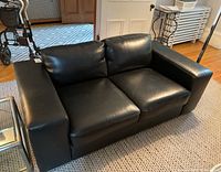 Angled front view of loveseat showing seat cushions, back cushions, and left arm.