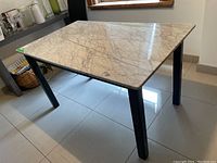Angled view of entire table showing marble surface and wooden legs