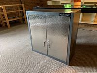 Front and angled views of the Mastercraft metal cabinet showing diamond plate patterned doors, handles and lock slots.