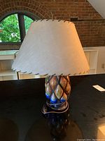 Full view of the table lamp showing the fabric lampshade and ceramic base with metal lattice.
