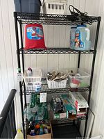 Utility shelf with various items stored on its shelves including plastic containers, bottles, and miscellaneous household items. Showing details of shelf construction and condition.