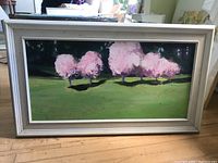 Front view of framed oil painting showing pink trees and green field