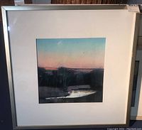 Full view of the framed pastel artwork showing the landscape scene with trees, water, and sky, framed in a white mat and metal frame.