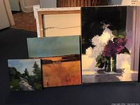 Three paintings displayed side by side: small square rock landscape at left, wide wheat field in center, tall lilacs still life at right