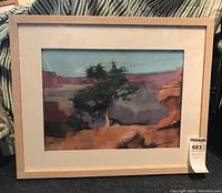 Framed landscape painting with tree and reddish rocks, showing full frame and matting, including artist signature visible in lower right corner.