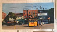 Full view of landscape-oriented painting depicting urban street scene with yellow parking booth and brick storefronts