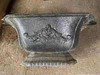 Full side profile of the cast iron planter showing shape, texture, and raised decorative details.