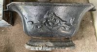 Side view of cast iron planter showing ornate design and overall shape.