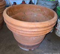 Front and side view of large terracotta clay planter showing ring moldings on rim and tapered base with visible wear.