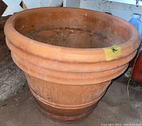 Front angled view of large clay planter showing terracotta surface and wide rim.