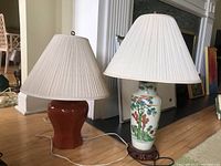 Both lamps side by side on floor showing red ceramic lamp on left and porcelain vase lamp on right