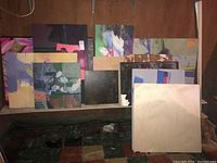 Multiple art boards arranged on shelf and floor in basement