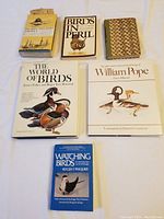Six bird books arranged on a flat surface, titles and covers visible including 'The World of Birds', 'Birds in Peril', and a William Pope book.