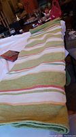 Photo of a striped picnic blanket laid out over a surface in an indoor setting.