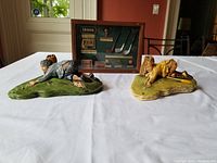 Photo of two funny golf statues and a golf shadow box on a table.