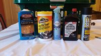 Image showing wood cleaner, fabric protectant, air freshener, dark brown bottle, and leak seal spray arranged on table.