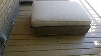 Photo of large outdoor ottoman with beige Belgian linen cushion on neutral grey woven base.