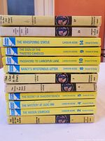 Stacked spines of 12 Nancy Drew books showing titles and authors.